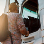 Back view of driver getting into truck cabin.